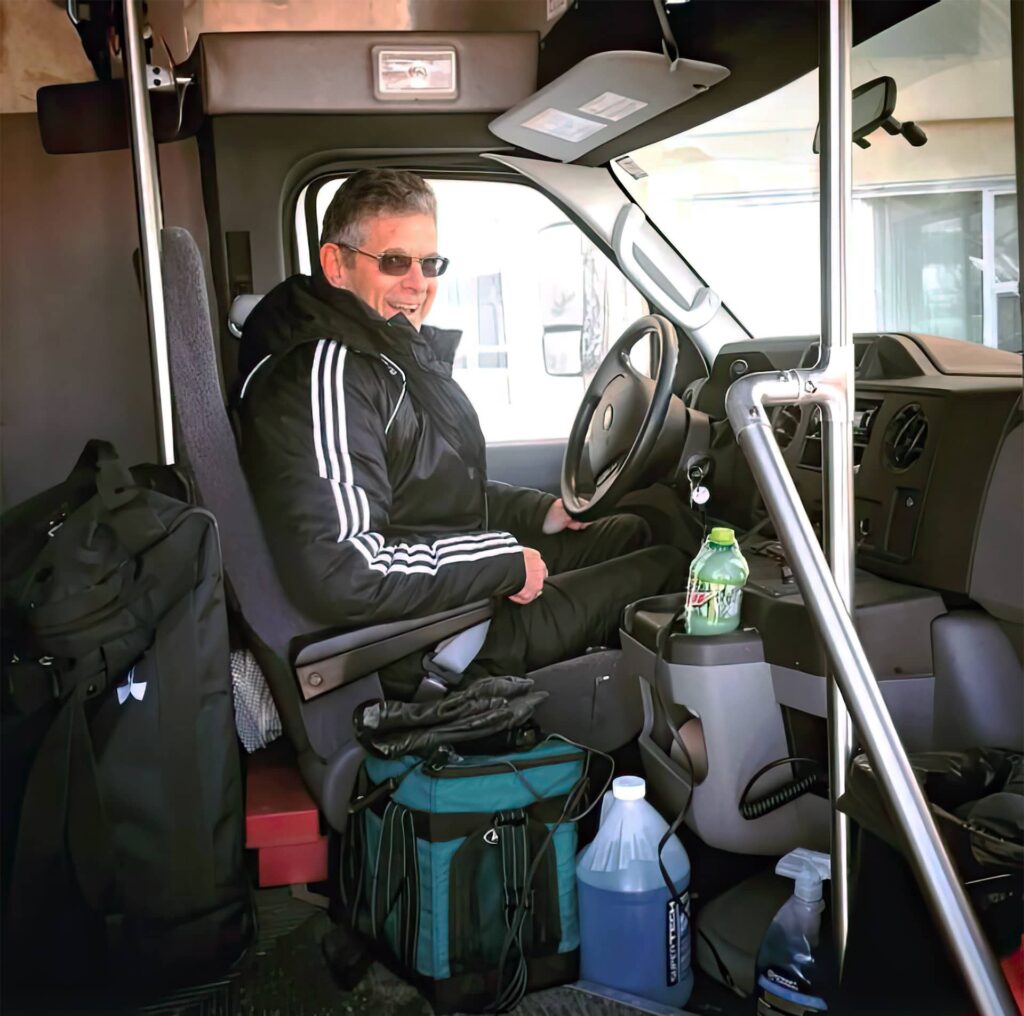 photo of Ronnie Guy behind the wheel of an athletics bus