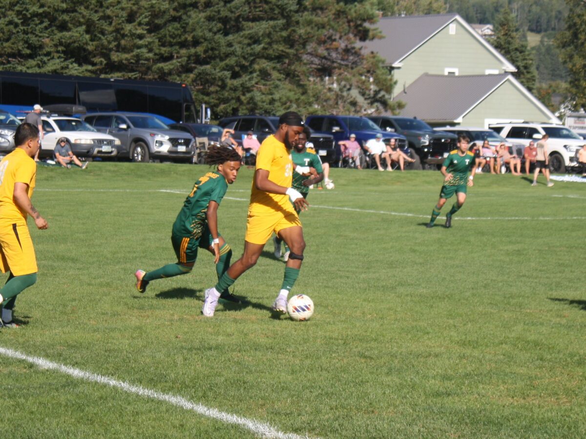 a men's soccer player takes posession of the ball