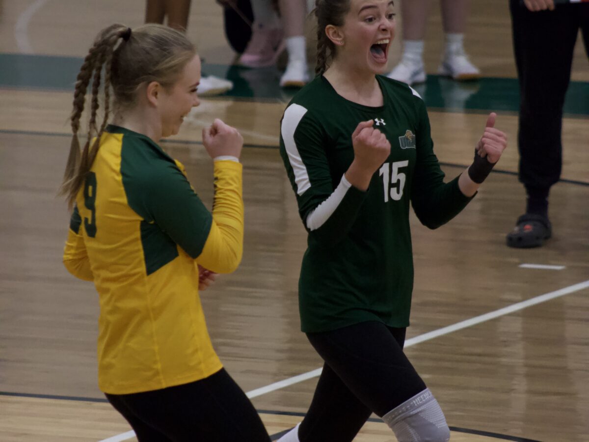 two volleyball players celebrate on the court