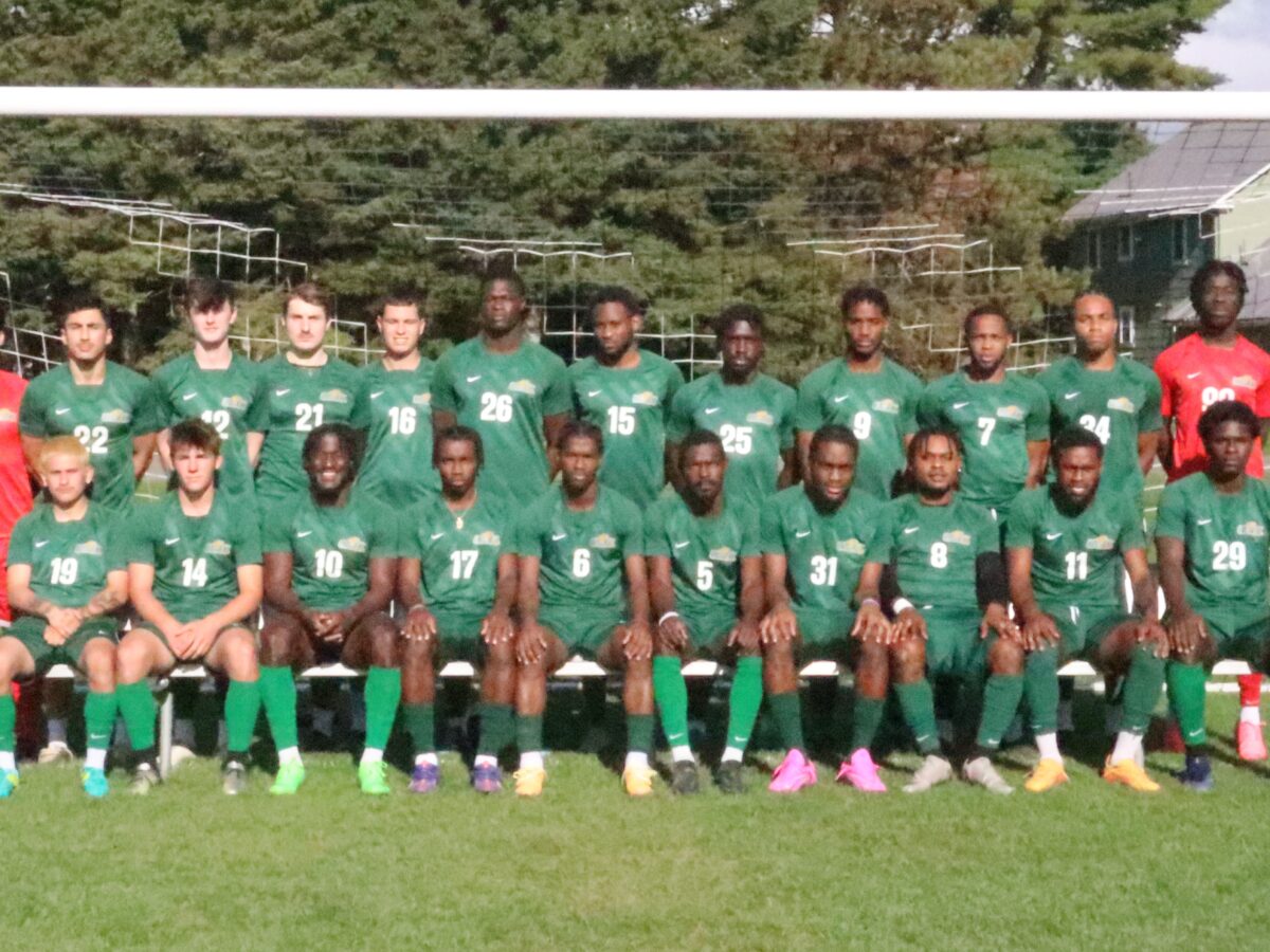 group photo of the men's soccer team in front of a soccer goal