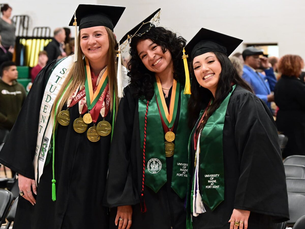 three female UMFK graduates pose together and smile for the camera during the 2024 commencement ceremony